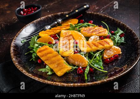 Salade d'été avec fromage Halloumi grillé, arugula, oranges et grenade.Arrière-plan sombre.Vue de dessus Banque D'Images