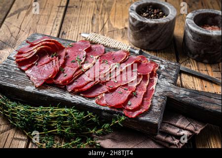 Tranches de pastrami séchées, viande de bœuf aux herbes sur bois.Arrière-plan en bois.Vue de dessus Banque D'Images