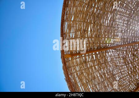 Partie d'un parasol tressé depuis la vue de dessous des branches.Parasol en osier sur fond bleu ciel.Gros plan.Copier l'espace.Mise au point sélective. Banque D'Images