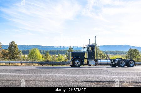 Puissant tracteur semi-remorque noir industriel sans semi-remorque sur la route sinueuse et étroite à travers la forêt d'automne de Columbia Gor Banque D'Images