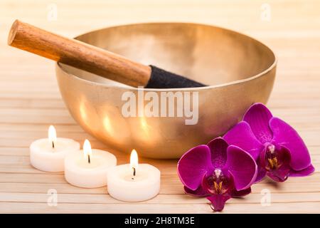 Bol de chant avec bougies allumées et fleurs d'orchidées Banque D'Images