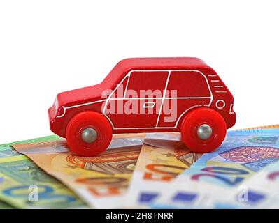 voiture jouet en bois rouge sur des billets en euros isolés sur fond blanc avec espace de copie Banque D'Images