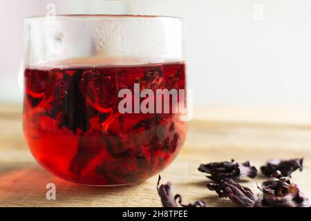 Une tasse de verre avec thé hibiscus rouge se tient sur une table en bois.La boisson a une couleur rouge vif grâce aux fleurs de la rose soudanaise.D traditionnel Banque D'Images