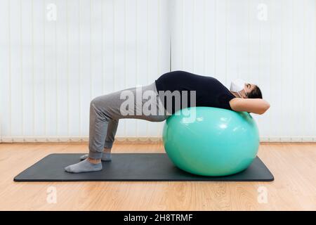 Une femme enceinte se reposant sur son dos sur un ballon de fitness faisant des exercices Banque D'Images