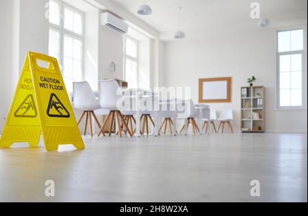 Salle de classe où le préposé au nettoyage a placé l'affiche indiquant attention sol mouillé Banque D'Images