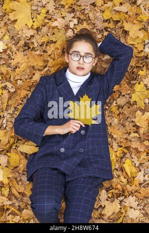 Vue de dessus portrait de jeune belle femme couché dans les feuilles d'automne Banque D'Images