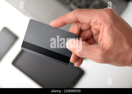 Concept de paiement électronique avec la main montrant la carte de crédit avec les appareils mobiles en arrière-plan.Vue de dessus. Banque D'Images