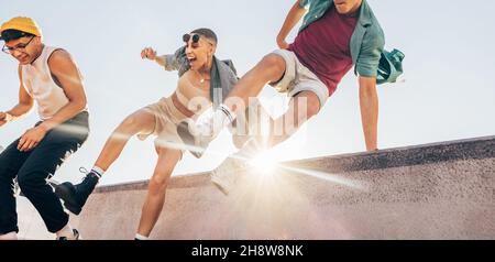 Des amis énergiques qui sautent sur un mur à l'extérieur.Groupe multiethnique de jeunes qui s'amusent ensemble au soleil.Groupe d'amis joyeux se sentant vibr Banque D'Images