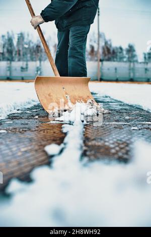 Le concierge nettoie la zone de neige avec une pelle en bois.Nettoyage des rues après les chutes de neige et le blizzard.Arrière-plan. Banque D'Images