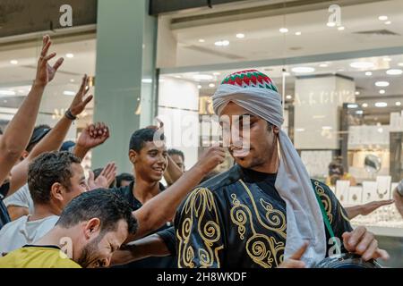 Portrait du jeune égyptien dans des vêtements traditionnels jouant du tambourin dans la rue en soirée. Banque D'Images