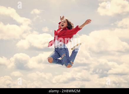 un enfant souriant sautant. insouciant et joyeux. style de mode pour les enfants. une adolescente sur fond de ciel à l'extérieur. un saut pour les enfants à l'arrière-plan. une bonne journée pour les enfants Banque D'Images