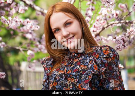 Beauté jeune fille posant près de fleur cerisier avec des fleurs roses.Parc de printemps Banque D'Images