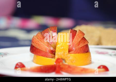 Pomme et cerise fraîchement tranchés sur une assiette blanche dans une forme unique Banque D'Images