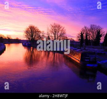 Le soleil brûlant rouge vient de se lever sur un canal bleu glacé et froid de Leeds et Liverpool lors d'un matin d'automne éclairant un bateau à Narrowboat avec une lueur orange Banque D'Images