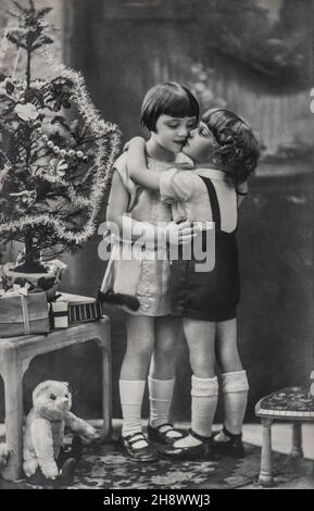 Enfants adorables avec arbre de Noël, cadeaux et jouets vintage.Image ancienne avec grain de film original Banque D'Images