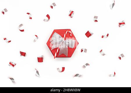 Coffret cadeau brillant rouge festif avec noeud argenté et confettis de canne à sucre isolés sur fond blanc.Noël, nouvel an, surprise.Copier l'espace Banque D'Images