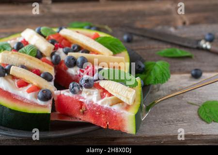 Petit-déjeuner de remise en forme ou en-cas pour la saison estivale avec des tranches de pastèque, garnies de puits de soleil, et des fruits frais Banque D'Images