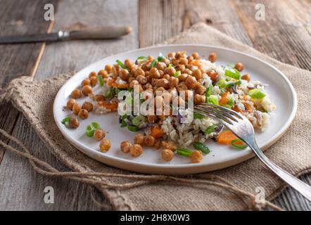 Plat végétalien avec riz sauvage et riz basmati, légumes et pois chiches rôtis sur une assiette Banque D'Images