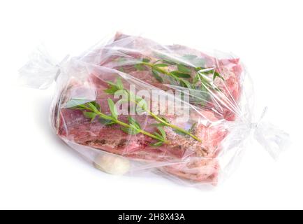 Viande fraîche emballée dans une pochette spéciale pour la cuisson.Poitrine de porc avec légumes verts.Isolé sur fond blanc. Banque D'Images