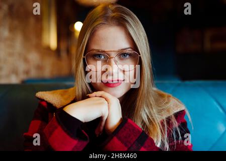 Une jeune femme blonde confiante assise dans un café et regardant l'appareil photo Banque D'Images