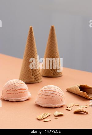 Une cuillère à glace rose et des gaufres sont placées sur une table en studio Banque D'Images
