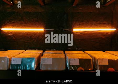Porte-disques en vinyle musical en abondance placé sur un mur noir avec des lampes lumineuses en magasin avec un éclairage tamisé Banque D'Images