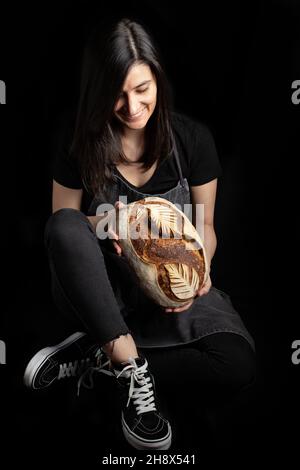 Jeune femme indépendante concentrée dans des vêtements décontractés assis sur une chaise avec les yeux fermés, l'ordinateur portable est utilisé pour travailler sur le projet appartement moderne et lumineux Banque D'Images