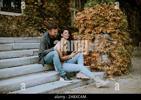 Beau jeune couple assis sur les escaliers extérieurs un jour d'automne Banque D'Images