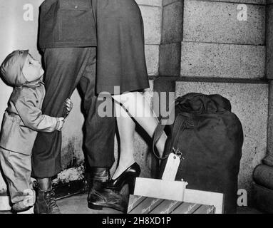 Jeune, embrassant son Père soldat, regardant vers le haut tandis que le soldat lève sa femme du sol pour lui souhaiter un « joyeux Noël », U.S. Office of War information, décembre 1944 Banque D'Images