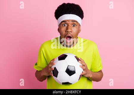 Photo de l'étonnant choqué afro américain jeune homme tient les mains football isolé sur fond rose couleur Banque D'Images