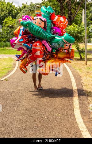 Goias, Brésil – 1er décembre 2021 : le vendeur de ballons dans un parc.Une personne tenant plusieurs ballons qui cachent son corps entier. Banque D'Images