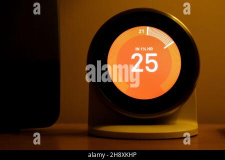 Un thermostat d'apprentissage intelligent de chauffage à la maison Nest situé dans une maison et réglé pour augmenter la chaleur à 25 degrés de sa température ambiante actuelle Banque D'Images