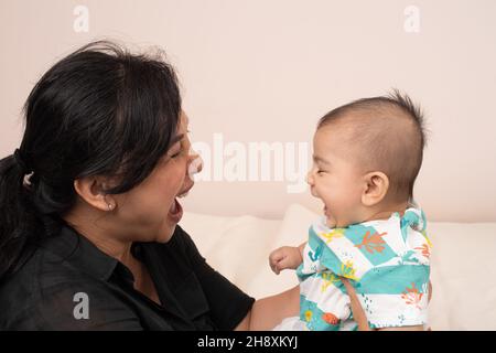 bébé garçon de 3 mois interaction avec la mère correspondant expressions, rire, bouche ouverte Banque D'Images