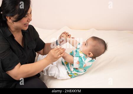 bébé garçon de 3 mois avec mère, tiré en position assise comme elle le tire par ses mains Banque D'Images