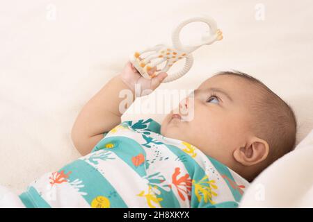 bébé garçon de 3 mois gros plan sur le dos regardant le jouet qu'il tient dans sa main Banque D'Images