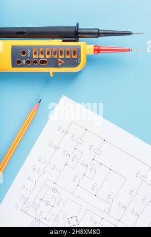 Indicateur de tension jaune avec un schéma électrique sur fond bleu.Test et vérification des réseaux électriques Banque D'Images
