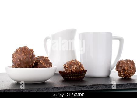 Plusieurs sucreries au chocolat avec des noix et des plats en céramique blanche, en gros plan, isolées sur du blanc. Banque D'Images