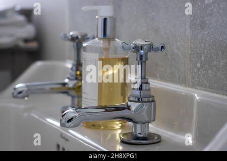 Robinets de salle de bains chromés et un peu de savon liquide pour les mains Banque D'Images