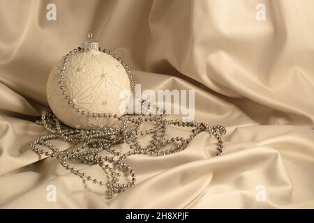 Concept Noël et nouvel an.Carte de Noël avec boule sur fond de soie ivoire.Boule de Noël et espace de copie pour le texte Banque D'Images