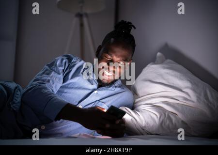 Regarder un téléphone portable avant de dormir la nuit dans la chambre Banque D'Images