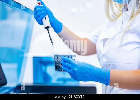 Préparation d'échantillons de sang dans un laboratoire.Une infirmière dans un laboratoire met les réactifs dans des tubes à essai avec du sang. Banque D'Images