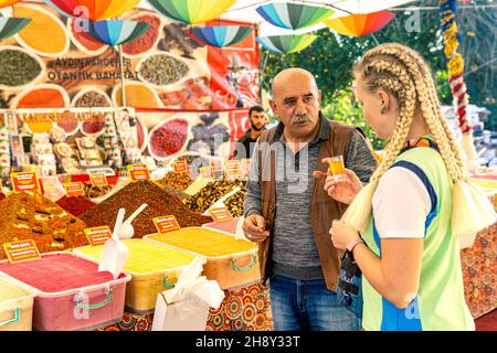 Kemer, Turquie - 08 novembre 2021 : le marchand de bazar invite un touriste à goûter le thé au gingembre Banque D'Images