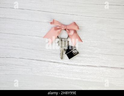 Nouvelles clés d'une maison argent avec porte-clés de petite maison vue de dessus avec espace de copie et fond en bois blanc, Banque D'Images