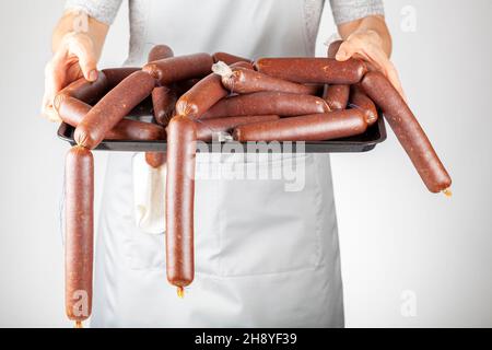 Une femme chef montre un tas de sucuk turc maison ou de saucisse sur un plateau fermenté transformé concept de consommation de viande rouge épicée. Banque D'Images