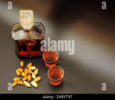 Amaretto, liqueur italienne forte avec amandes en bouteille et deux verres sur fond noir isolé.Gros plan. Banque D'Images