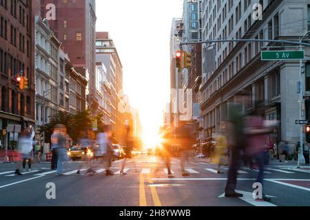 Les rues animées sont bondées avec des gens à une intersection sur la Cinquième Avenue à New York City avec la lumière du soleil qui brille entre les bâtiments de fond Banque D'Images