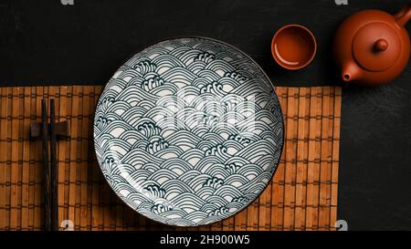 Table de style asiatique avec assiette en porcelaine avec baguette et table à manger avec thé asiatique. Vue sur le dessus Banque D'Images