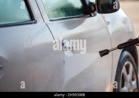 main avec lave-linge haute pression lave-linge de voiture blanche au poste de lavage de voiture en libre service public Banque D'Images