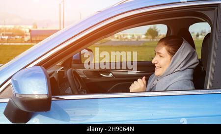 La femme écoute de la musique et danse en voiture le jour sombre Banque D'Images