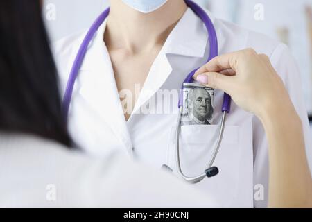 Une patiente a mis un billet de banque dans la poche des médecins sur rendez-vous pour un meilleur service Banque D'Images